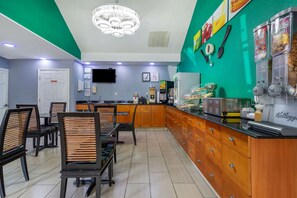 A restaurant with wooden cabinets, a counter with food items, and a television on the wall. - Quality Inn Covington (Covington)