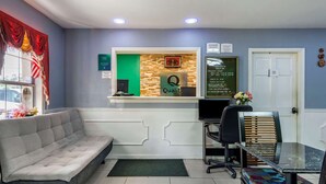 Zona de recepción con un letrero 'Qualit', un sofá, un escritorio y una silla.