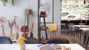 A modern interior with a dining area, hanging plants, and a bookshelf. - Hotel Paris Opera Affiliated by Meliá (Paris)