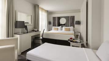 Habitación de hotel con cama, escritorio con silla, mesita de noche con lámpara y espejo grande.