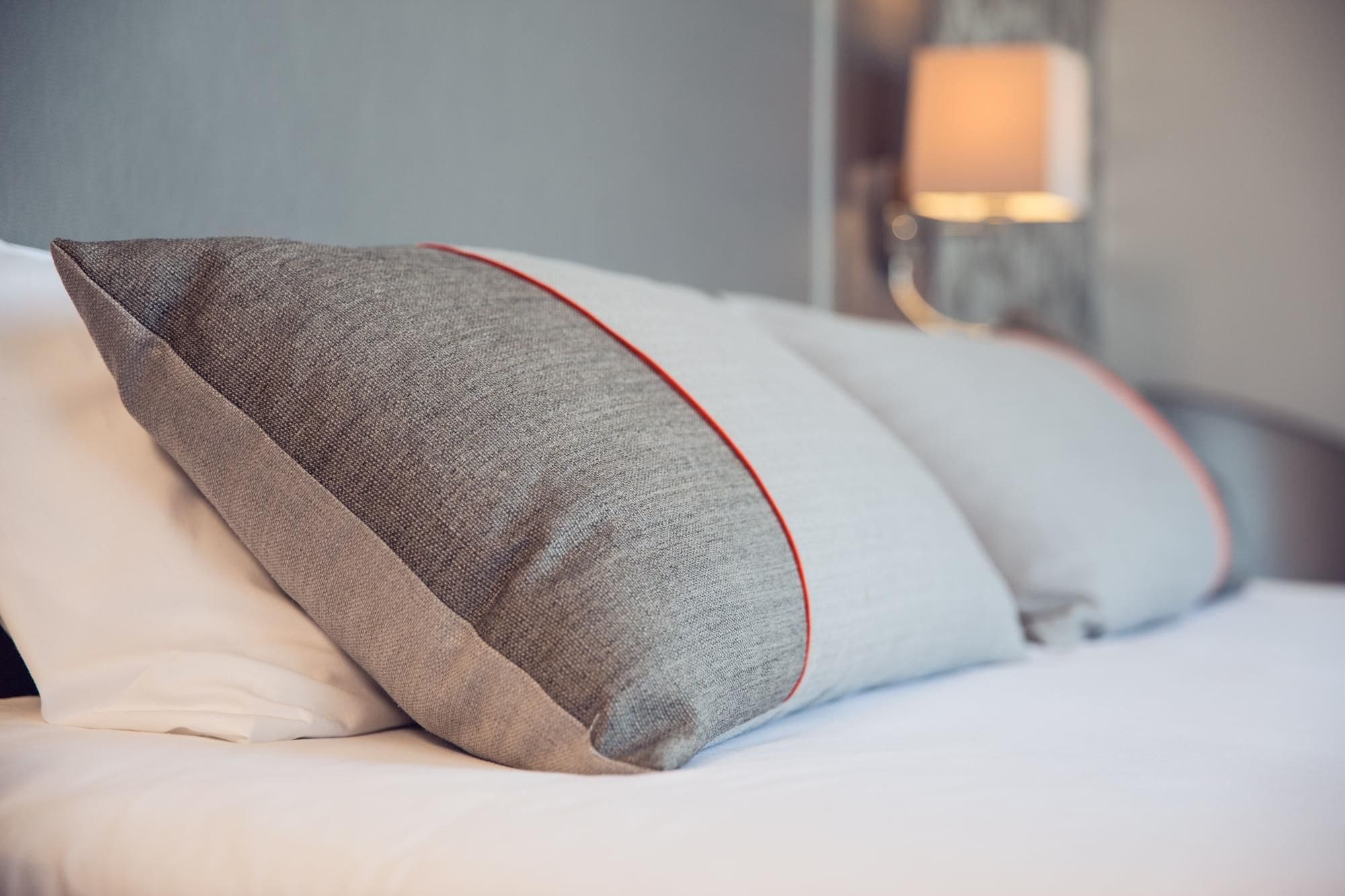 Un lit avec des oreillers et une lampe en arrière-plan.