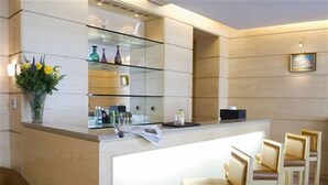 A reception area with a counter, bar stools, and a vase of flowers.