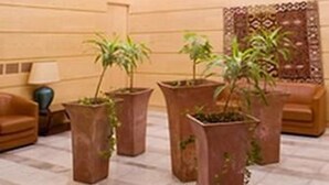 A lobby with a high ceiling, wooden panel walls, and several large potted plants.