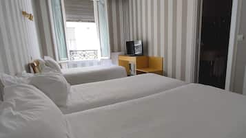 Ett hotellrum med två sängar, en tv på ett träbord och ett fönster med gardiner.