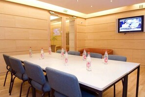 A conference room with a long table, blue chairs, and water bottles. - Grand Hôtel du Havre (Paris)