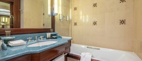 A bathroom with a double sink, a bathtub, and a large mirror.