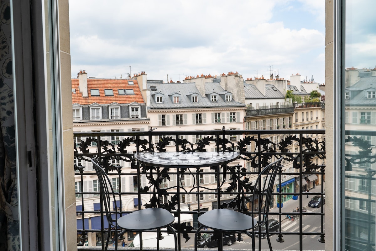 Un balcon doté d’une balustrade en fer forgé et de deux petites tables.