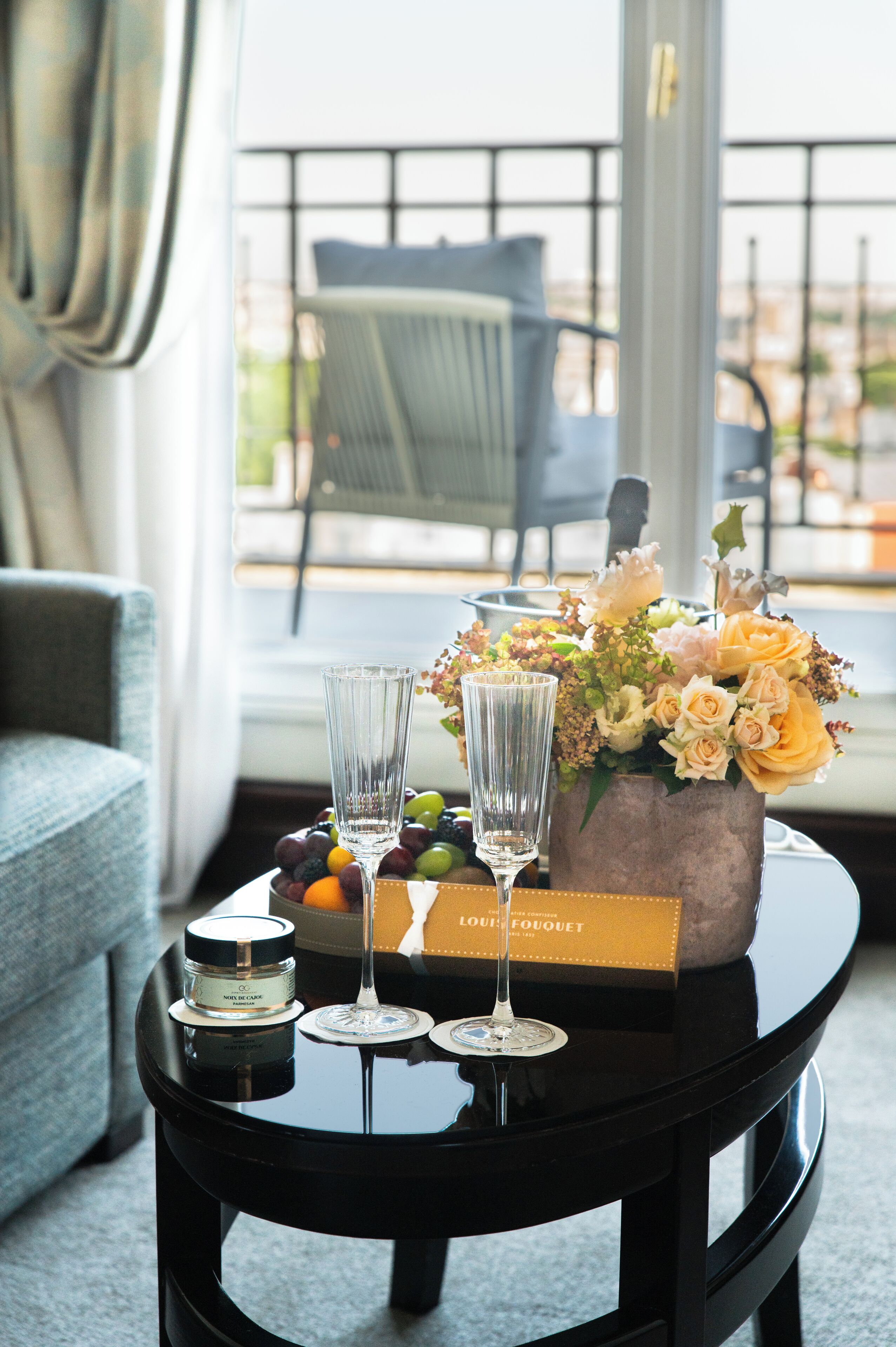A table with a bottle of perfume, two glasses, and a bouquet of flowers.