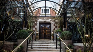 A grand entrance with a black double door, stone steps, and a glass canopy. - The Bloomsbury (London)
