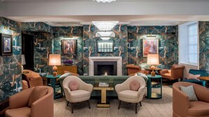 A room with a fireplace, patterned wallpaper, and comfortable seating. - The Bloomsbury (London)
