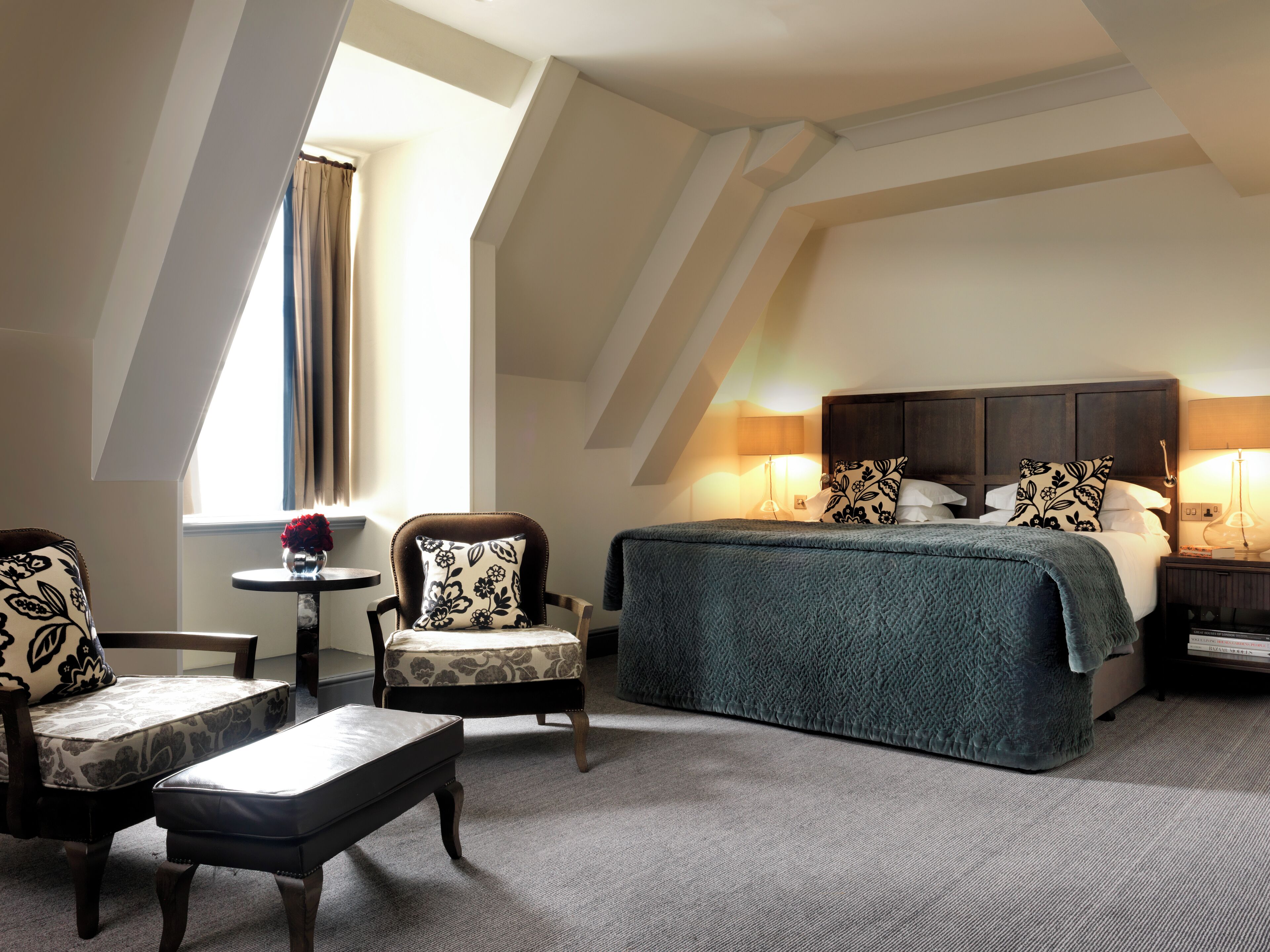 Habitación de hotel con una cama grande, una silla, una mesita y una ventana con cortinas.