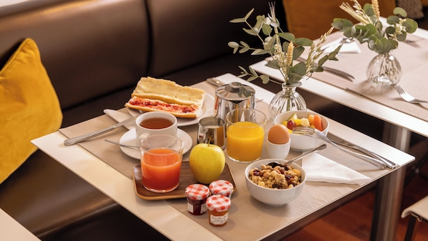 A breakfast tray with toast, juice, fruit, and a bowl of cereal on a table. - Villa des Ambassadeurs (Paris)