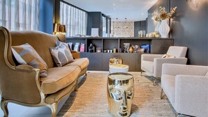 A modern living room with a brown sofa, a white armchair, and a unique glass coffee table. - Villa des Ambassadeurs (Paris)