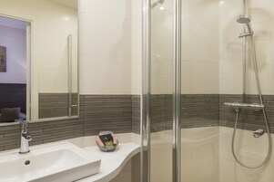 A modern bathroom with a glass-enclosed shower, a white sink, and a mirror with a black and white tile backsplash.
