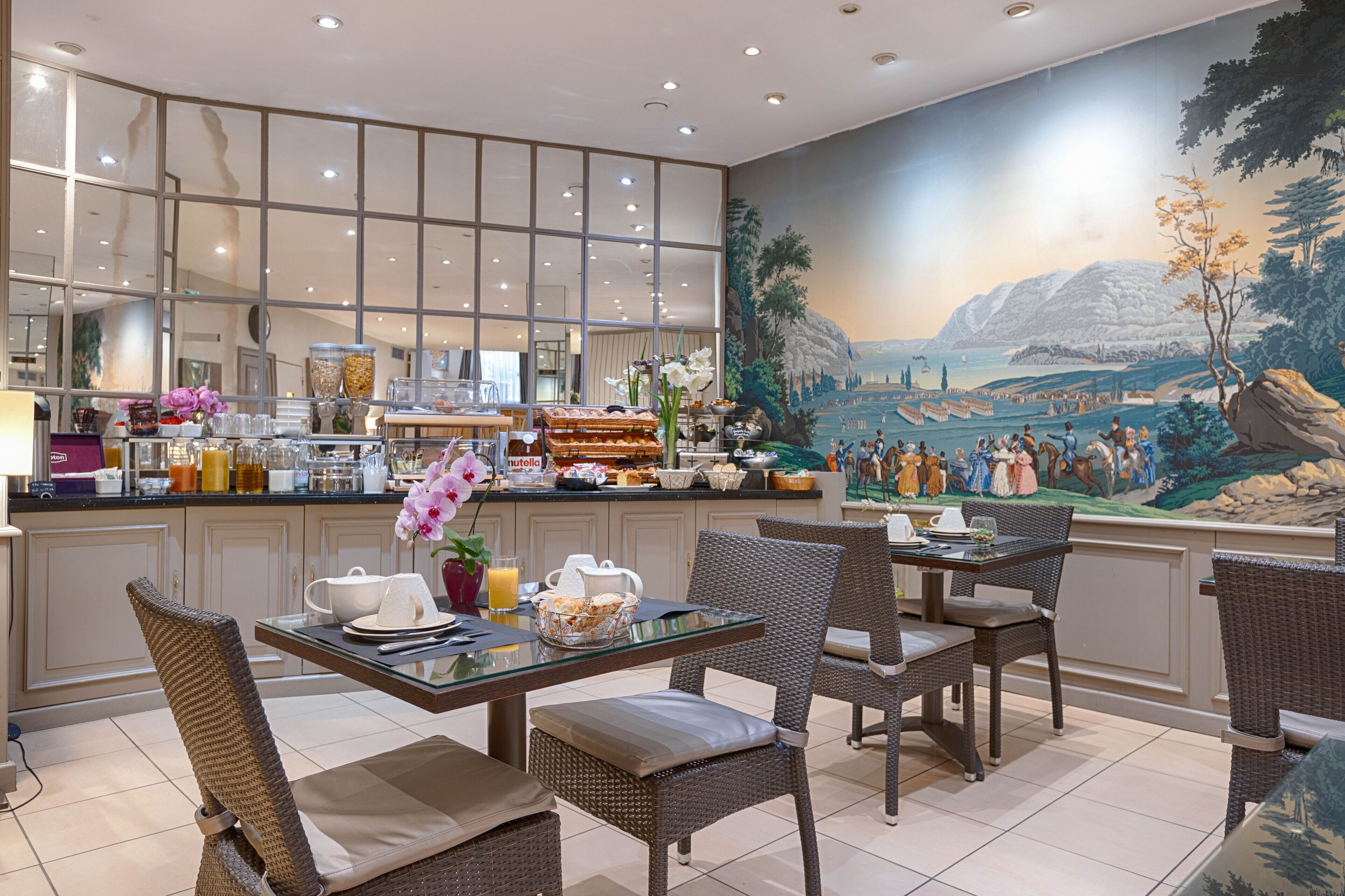 A dining area with wicker chairs, a glass table, and a buffet with various food items.