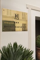 Eine goldene Plakette mit dem Schriftzug 'HOTEL BEAUGENCY' und einem Logo, an einer Wand angebracht.