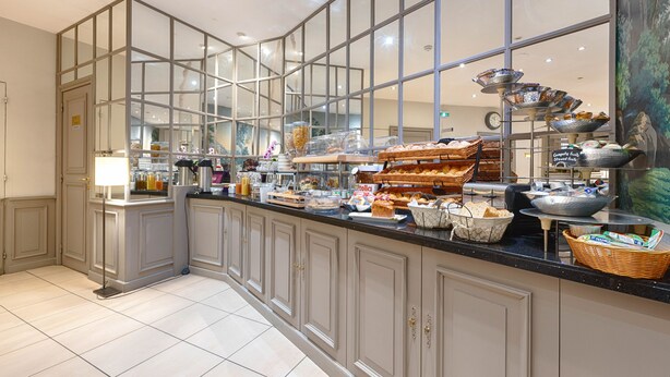 A buffet area with a variety of food items and a large window. - Beaugency Hotel (Paris)