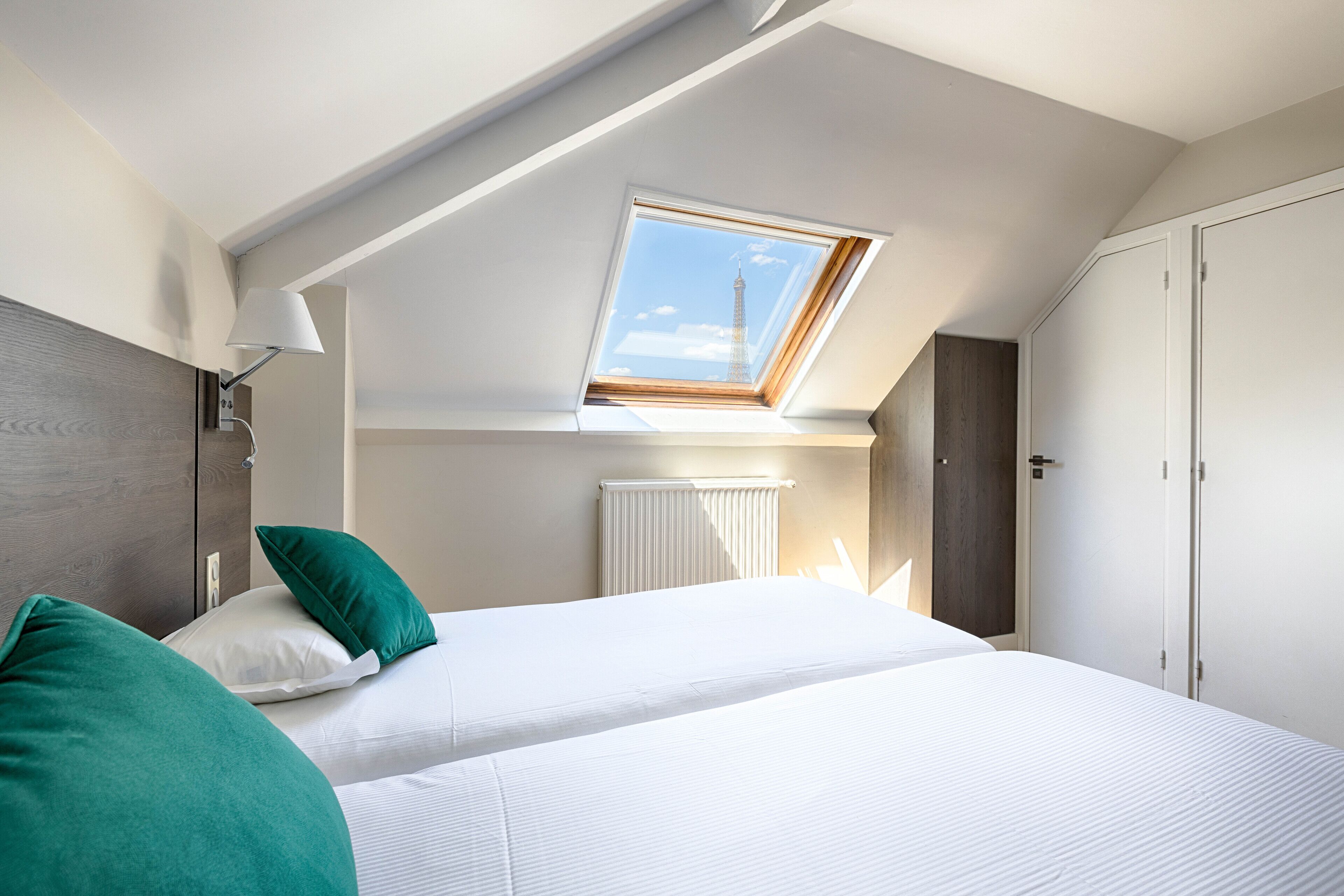 A bedroom with a skylight, a bed with white bedding, and a radiator.