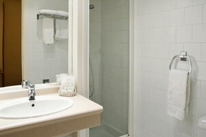 A bathroom with a sink, mirror, and a glass shower enclosure.