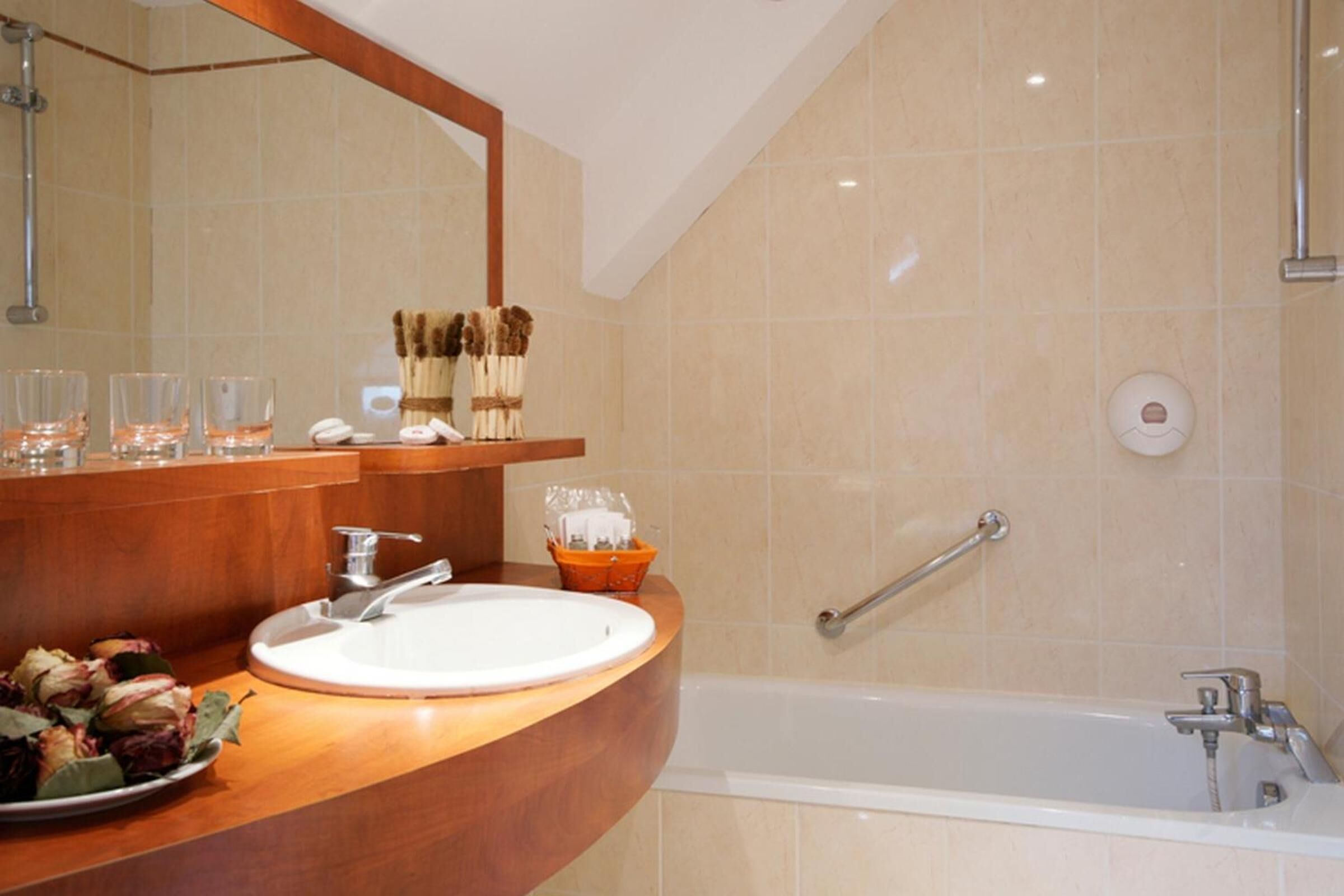 A bathroom with a wooden vanity, a sink, a mirror, and a bathtub.