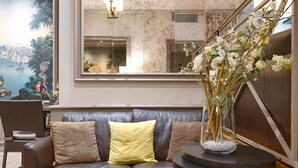 A modern living room with a leather sofa, a round table, and a vase of flowers. - Beaugency Hotel (Paris)