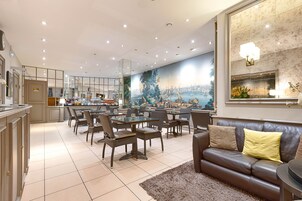 A spacious dining area with a large mural, a modern kitchen, and a leather sofa.