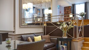 A modern living room with a leather sofa, a glass coffee table, and a bookshelf. - Beaugency Hotel (Paris)