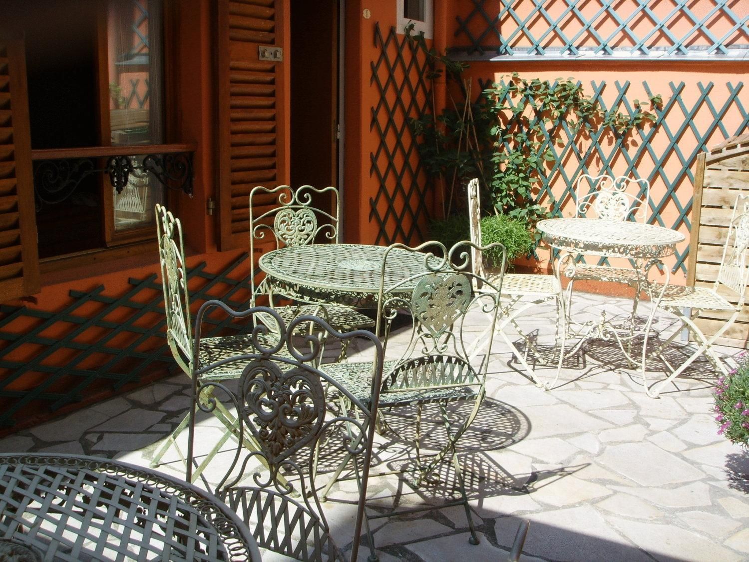 A patio with metal furniture, including a round table and chairs, and a small round table.