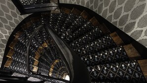 A spiral staircase with a patterned carpet and a stone wall. - Hôtel Palm - Astotel (Paris)
