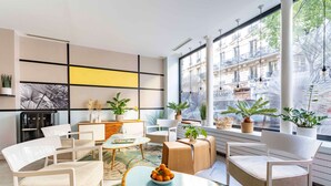 A modern living room with white furniture, a coffee table with fruit, and large windows with city views. - Hôtel Palm - Astotel (Paris)
