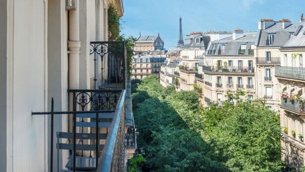 A view of a narrow street flanked by buildings with balconies, leading towards the Eiffel Tower. - Hôtel Palm - Astotel (Paris)