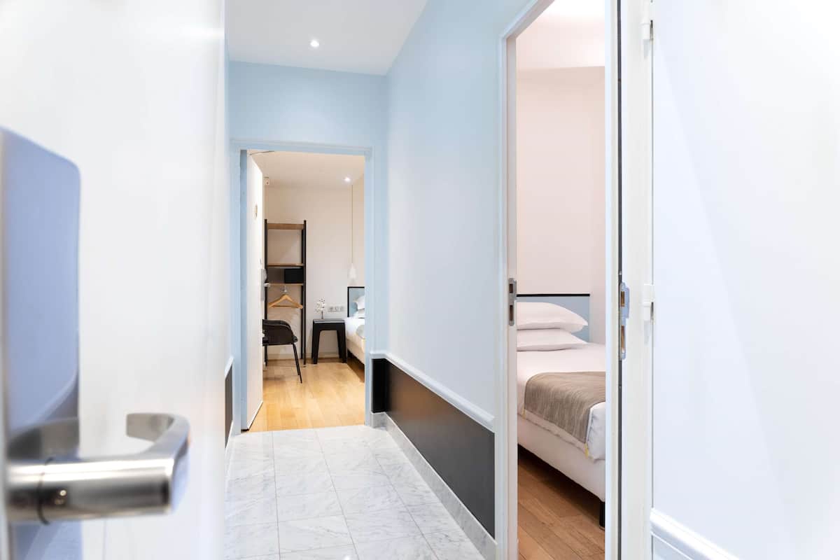 A hotel corridor with a bed, a desk, and a chair.