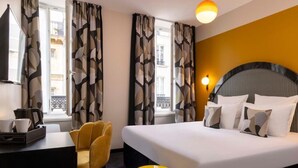A hotel room with a bed, a desk, a chair, a coffee maker, and a yellow trash bin. - Hotel Régina Opéra Grands Boulevards (Paris)