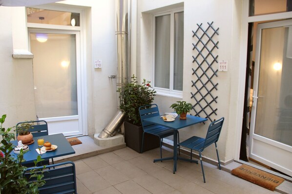 A small patio area with a table and chairs, a potted plant, and a window. - Hotel Régina Opéra Grands Boulevards (Paris)