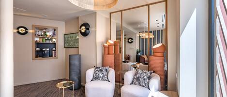 Una sala moderna con un sofá, sillones, una mesa de centro y una estantería.