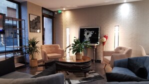 Un vestíbulo moderno con un sofá, sillones, una mesa de centro y una planta en maceta.