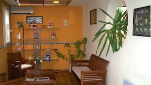 A reception area with wooden furniture, a plant, and a tiled wall. - Stars Antibes (Antibes)