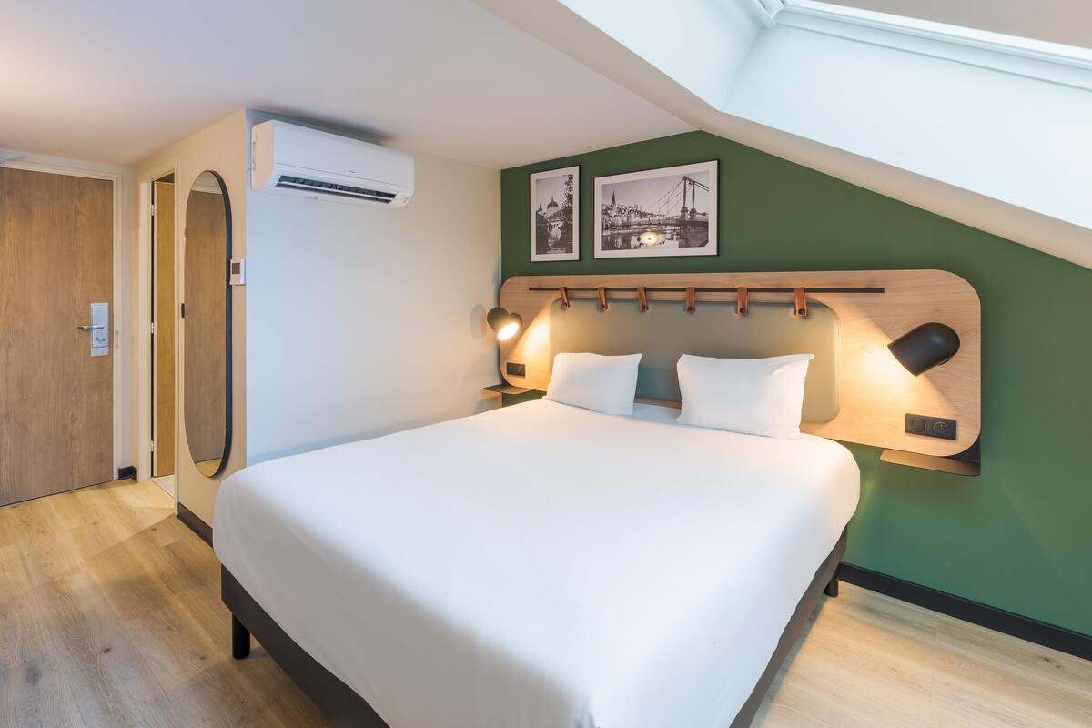 Een moderne hotelkamer met een groot bed, een bureau en een dakraam.