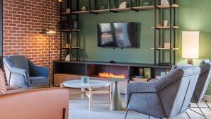 Un salon moderne avec un mur en briques, un téléviseur à écran plat et une cheminée.