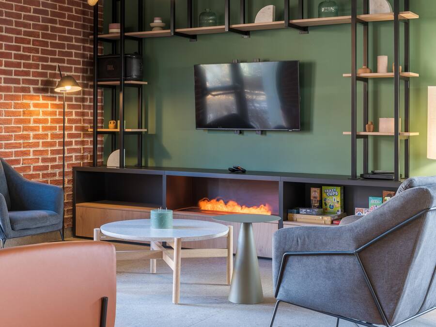 A modern lounge area with a brick wall, a flat-screen TV, and a fireplace.