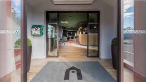 L’entrée d’un hôtel, avec un comptoir d’accueil, un espace salon et une vue dégagée sur l’intérieur.
