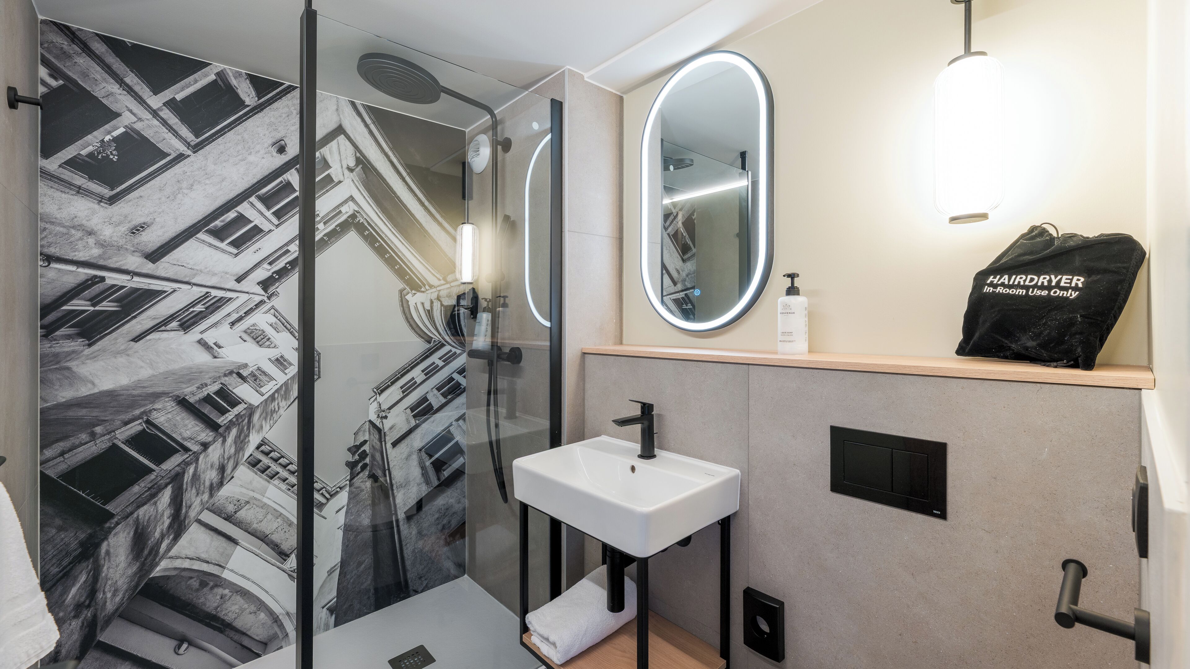 Ein modernes Badezimmer mit einer Glasdusche, einem weißen Waschbecken und einem Spiegel.