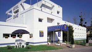 Un bâtiment blanc avec un auvent bleu et une enseigne sur laquelle on peut lire « HÔTEL STARS ».