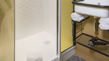 A modern bathroom with a glass-enclosed shower, a white sink with a black countertop, and a mirror above the sink.