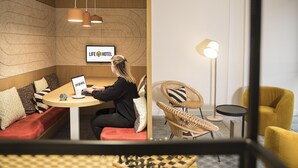 Une chambre d’hôtel moderne avec un mur en bois, un canapé, un bureau avec un ordinateur portable et une enseigne sur laquelle on peut lire « LIFE HOTEL ».