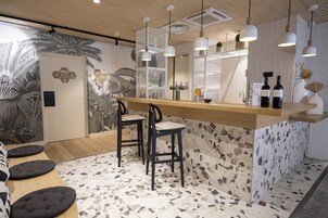 Un espace bar moderne avec un comptoir en bois, deux tabourets de bar et des luminaires suspendus.