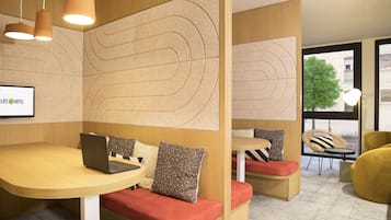 A modern hotel lobby with a round table, seating area, and a large window offering a view of the outside.
