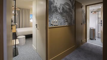 Een hotelkamer met een bed, een tafeltje, een stoel, een koffer en een kast.