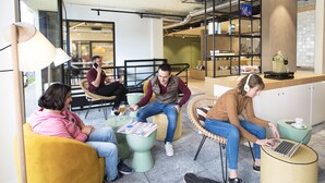 Un espace de travail partagé moderne, doté de coins salon, d’un espace café et d’un comptoir bien visible avec un distributeur de boissons.