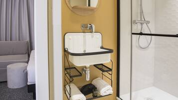 Une salle de bain moderne avec une douche à parois de verre, un lavabo blanc avec un miroir et un porte-serviettes.